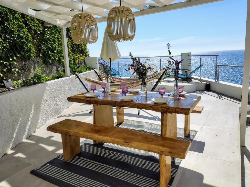 d'une table et d'un banc en bois sur un balcon donnant sur l'océan. dans l'établissement Conca Verde c21- BEACH FRONT little villas POOL, private JACUZZI sea view, à Marina dʼAndora