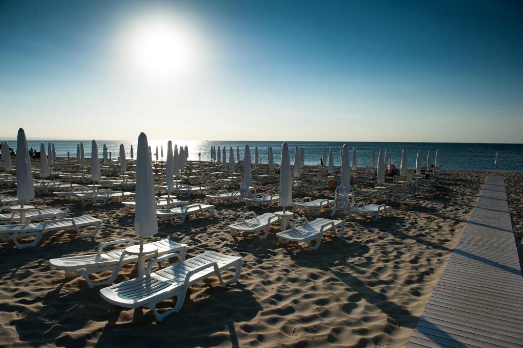 une plage avec des chaises longues et des parasols et l'océan dans l'établissement Stella Maris Hotel, à Marina di Ginosa