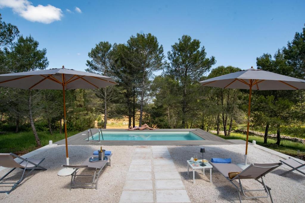 - une piscine avec 2 parasols et 2 chaises dans l'établissement Puglia Essence - Ancient Lamia & Exclusive Pool, à Martina Franca