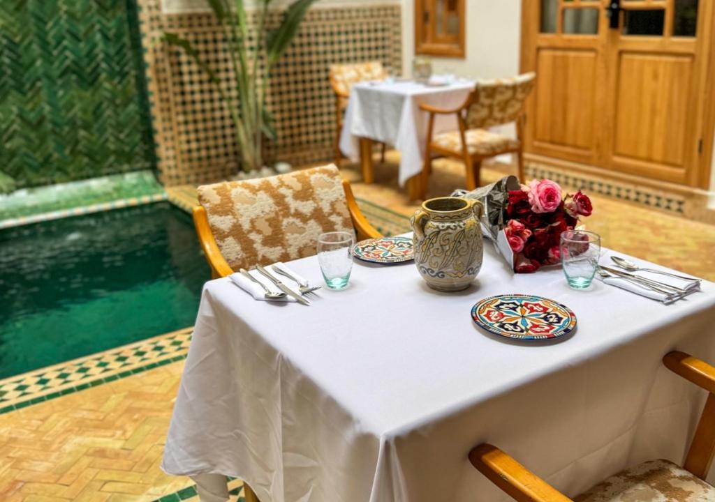 une table avec des assiettes et un vase avec des fleurs. dans l'établissement Riad Dar Timrad, à Fès