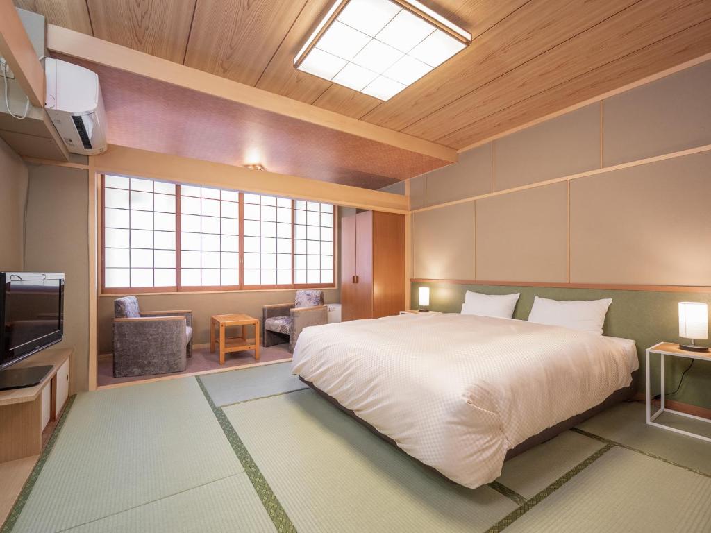 une chambre avec un grand lit et une télévision dans l'établissement Yumoto Kanko Hotel Saikyo, à Nagato
