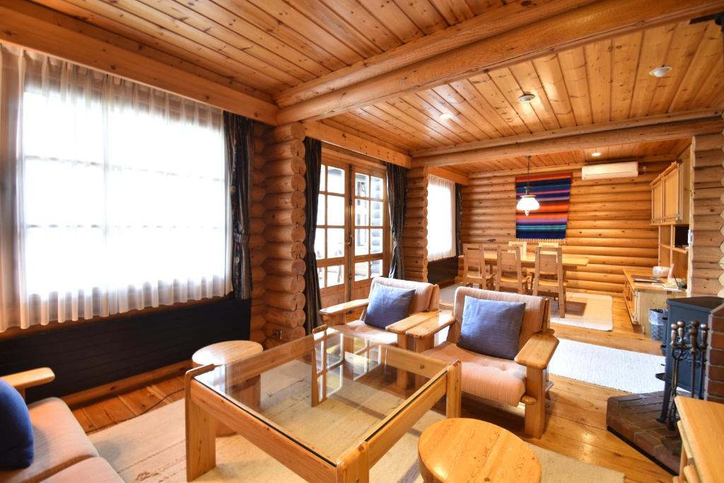 - un salon avec une table et des chaises dans une cabane en rondins dans l'établissement Hotel Nidom, à Tomakomai