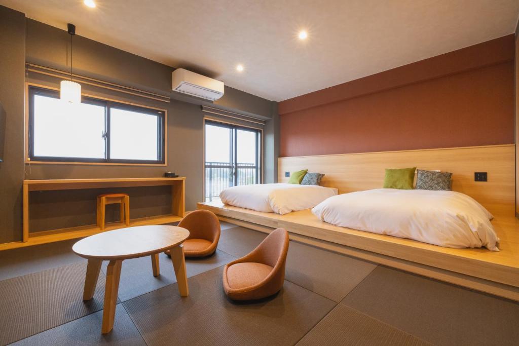 une chambre d'hôtel avec deux lits et une table et une table sidx sidx sidx sidx dans l'établissement 奥州平泉温泉旅館 itsumu, à Oshu