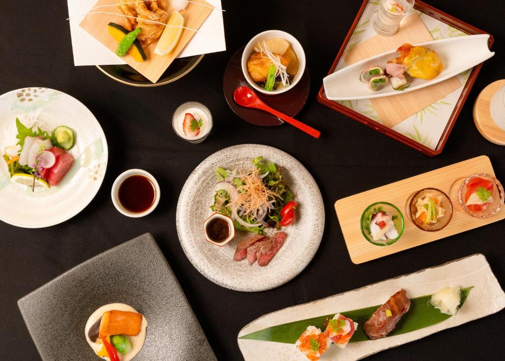 une table noire avec des plaques de nourriture dans l'établissement 奥州平泉温泉旅館 itsumu, à Oshu