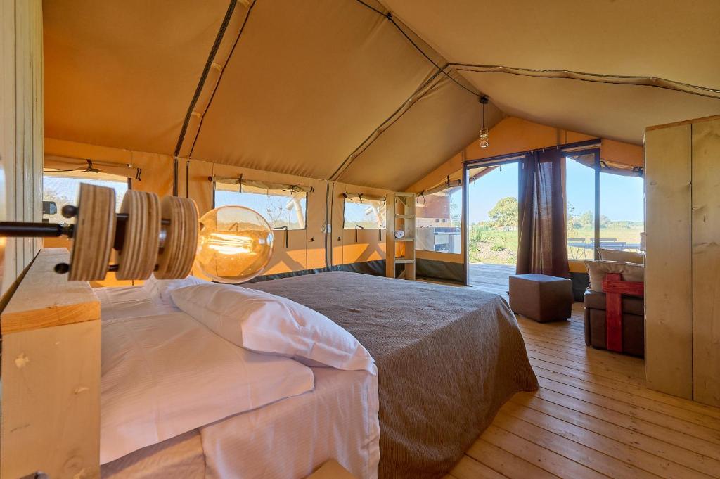 une chambre avec un grand lit dans une tente dans l'établissement Delfino Tuscany Resort, à Marina di Cecina