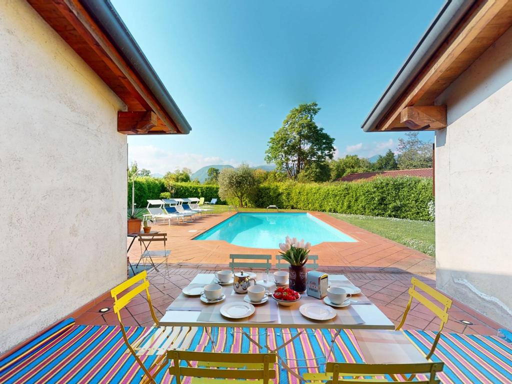 - une table avec des chaises à côté de la piscine dans l'établissement Villa Paradiso by Bookinggardalake, à San Felice del Benaco