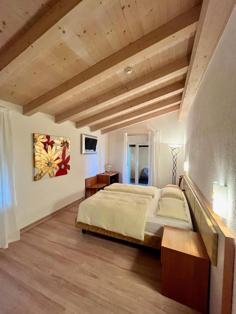 - une chambre avec un grand lit et du parquet dans l'établissement Hotel Villa Carmen, à Malcesine