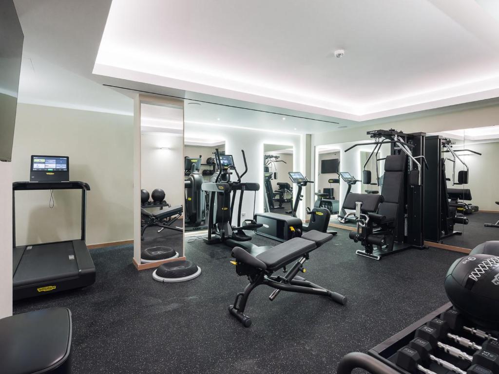 une salle de sport avec plusieurs machines de course et un miroir dans l'établissement San Vito Resort & Spa, à San Vito Lo Capo