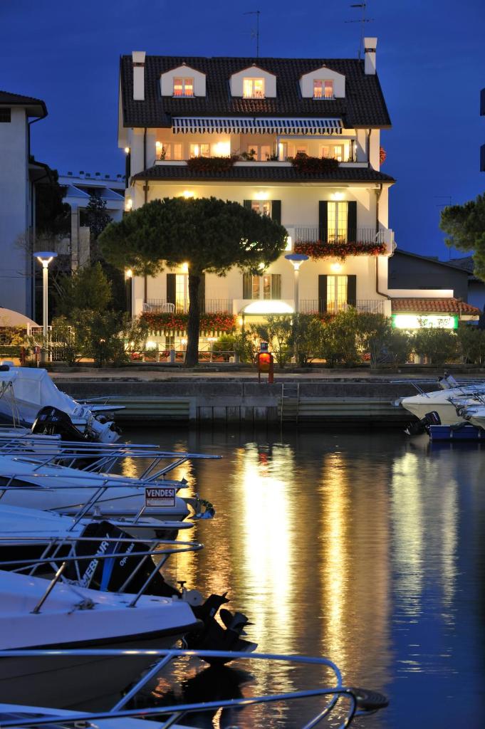 un bâtiment avec des bateaux dans une marina la nuit dans l'établissement Hotel La Goletta, à Lignano Sabbiadoro