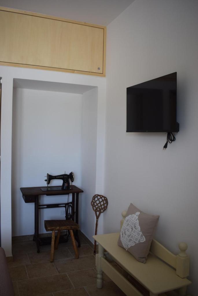 une pièce avec une télévision et une table avec un banc dans l'établissement Antichi Saperi - Villa con piscina Cisternino, à Cisternino