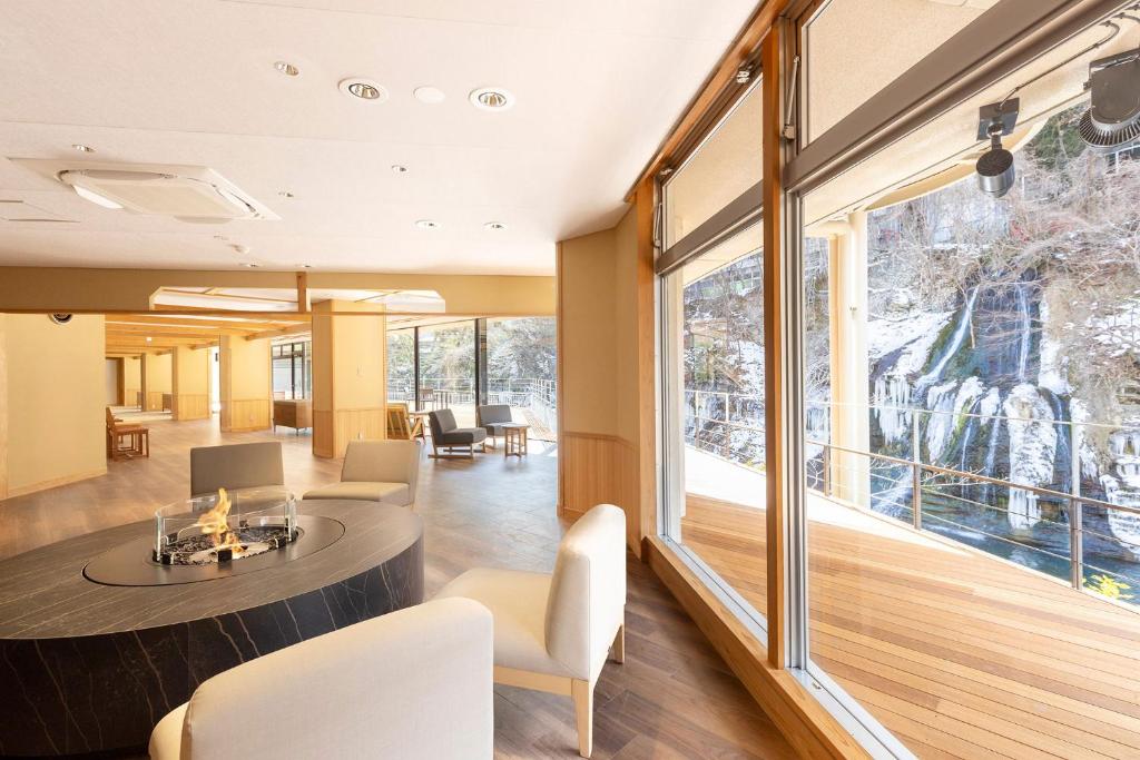 une pièce avec une table et des chaises et une grande fenêtre dans l'établissement Ooedo Onsen Monogatari Premium Hotel New Shiobara, à Nasushiobara