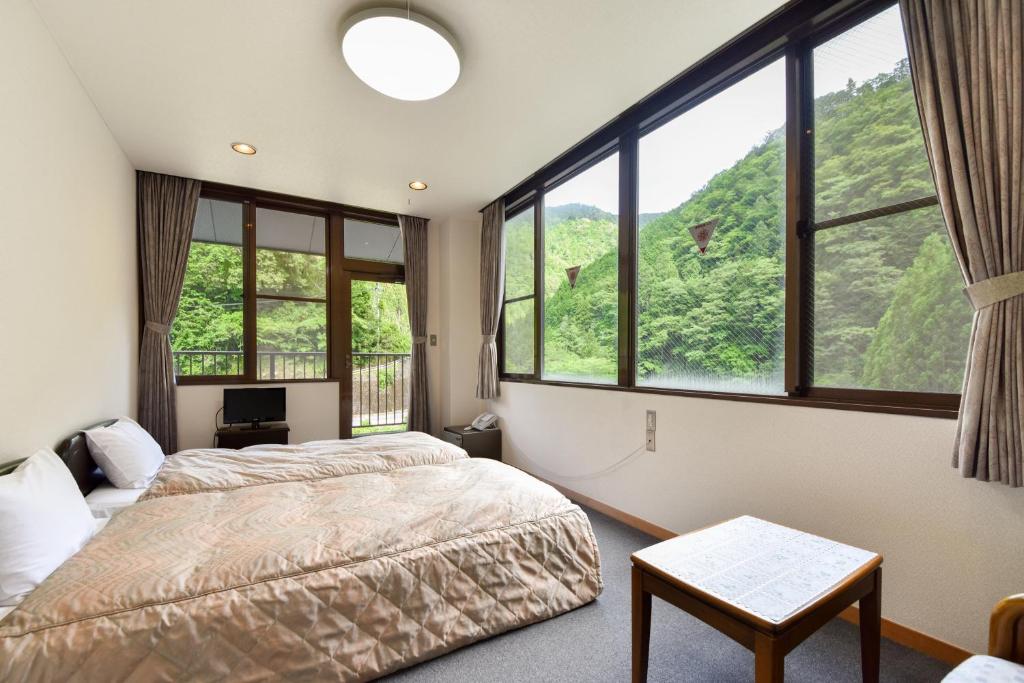 une chambre avec un lit et de grandes fenêtres dans l'établissement Bijintei, à Tanabe