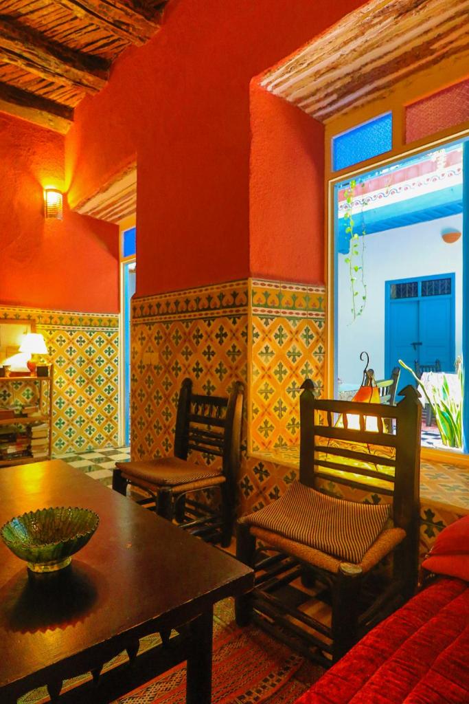 un salon avec une table et deux chaises ainsi qu'une chambre aux murs rouges dans l'établissement Les Matins Bleus, à Essaouira