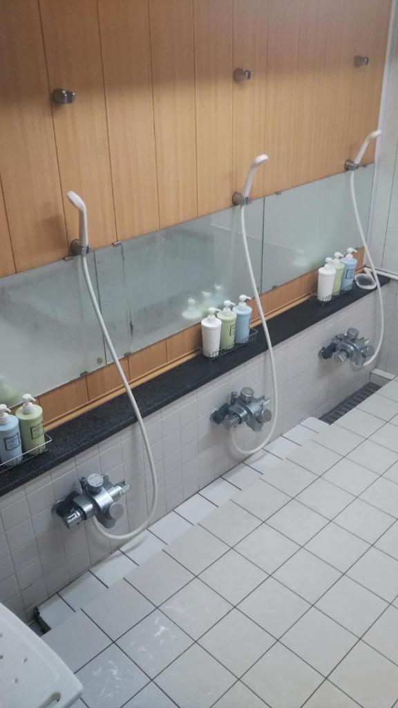 La salle de bains est pourvue de 2 pommeaux de douche sur un mur. dans l'établissement Kikunoya Ryokan, à Kanazawa