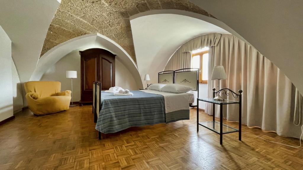 une chambre avec un lit et une chaise dans l'établissement La Corte di Leuca Residence, à Leuca