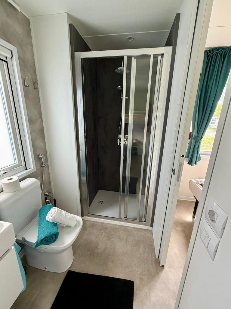 une salle de bain avec toilettes et douche en verre dans l'établissement Bungalow Lido MAREA, direkt at the lake & in center, à Colico 6 autres photos