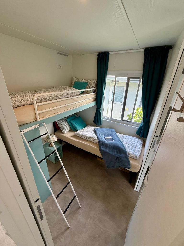 une petite chambre avec deux lits superposés et une fenêtre dans l'établissement Bungalow Lido MAREA, direkt at the lake & in center, à Colico