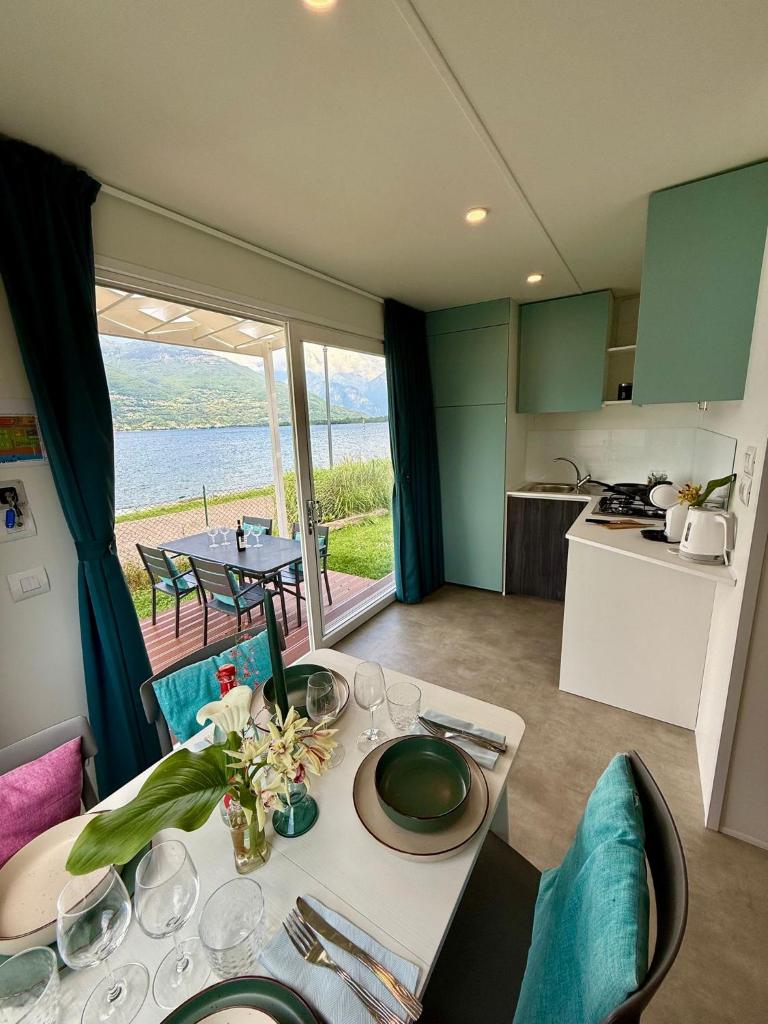 une cuisine et un salon avec une table et une cuisine et une vue dans l'établissement Bungalow Lido MAREA, direkt at the lake & in center, à Colico