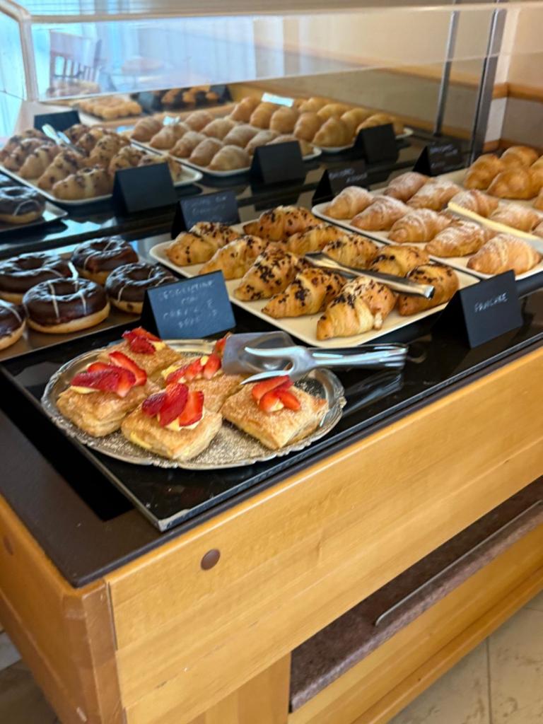 une vitrine avec de nombreux types différents de pâtisseries et de beignets dans l'établissement Hotel Fortuna, à Chioggia