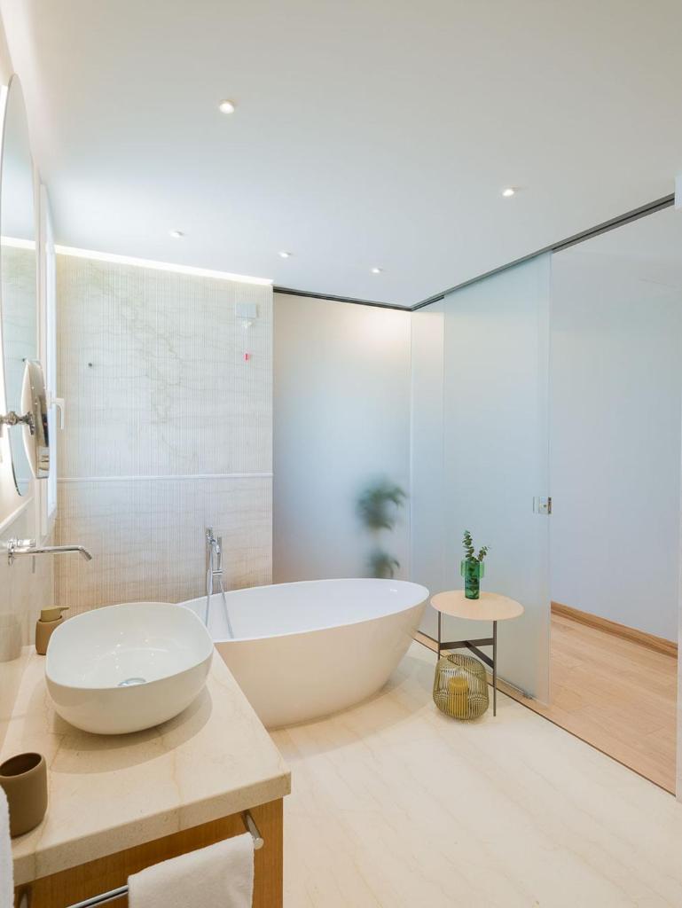 La salle de bains est pourvue d'une grande baignoire blanche et d'un lavabo. dans l'établissement San Vito Resort & Spa, à San Vito Lo Capo