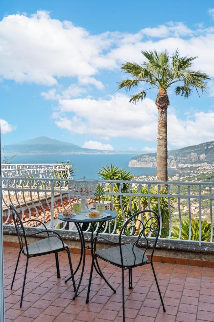 un patio avec une table, des chaises et un palmier dans l'établissement Villa Giu Giu vista mare con piscina a Sorrento, à Sorrente