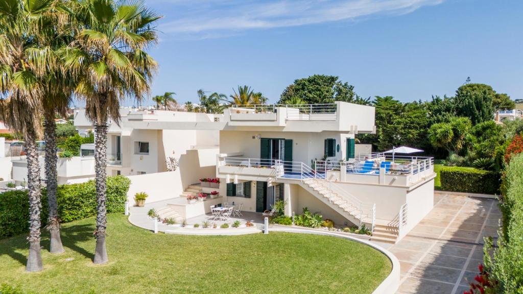 - une vue aérienne sur une maison blanche avec des palmiers dans l'établissement Villa Vulcano, à Marina di Ragusa
