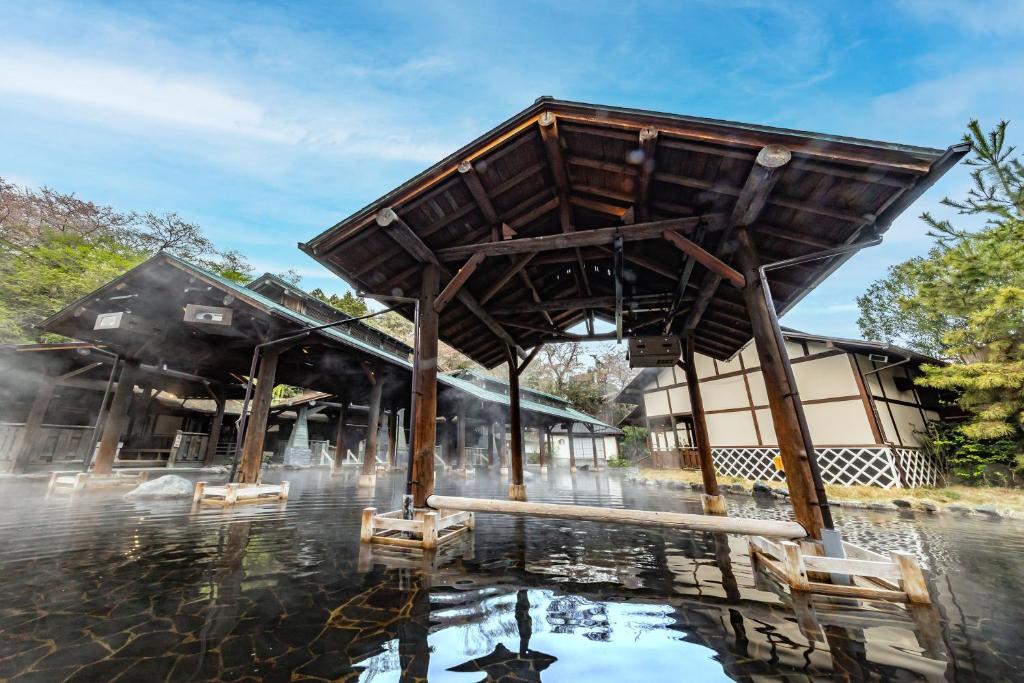 un pavillon dans l'eau devant un bâtiment dans l'établissement Spa Resort Hawaiians Hotel Hawaiians, à Iwaki