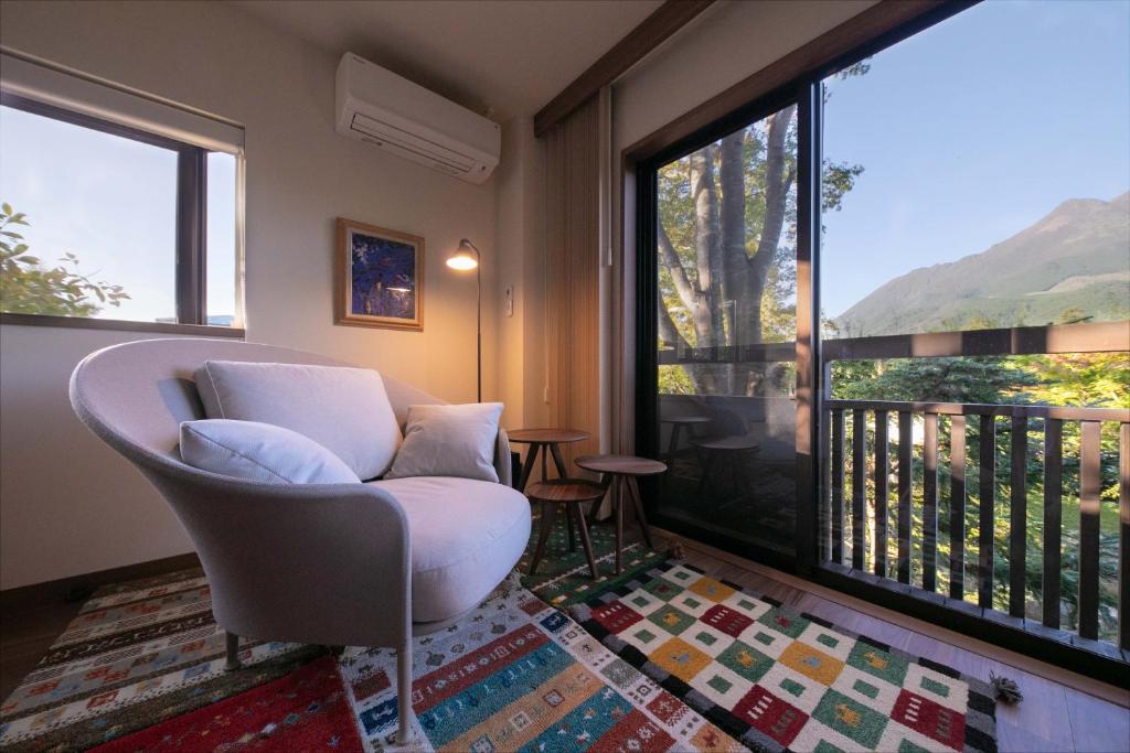 un salon avec une chaise et une grande fenêtre dans l'établissement Saigakukan, à Yufu