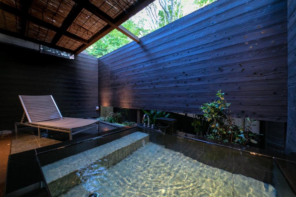 une piscine dans une maison avec une chaise et un banc dans l'établissement Saigakukan, à Yufu 163 autres photos