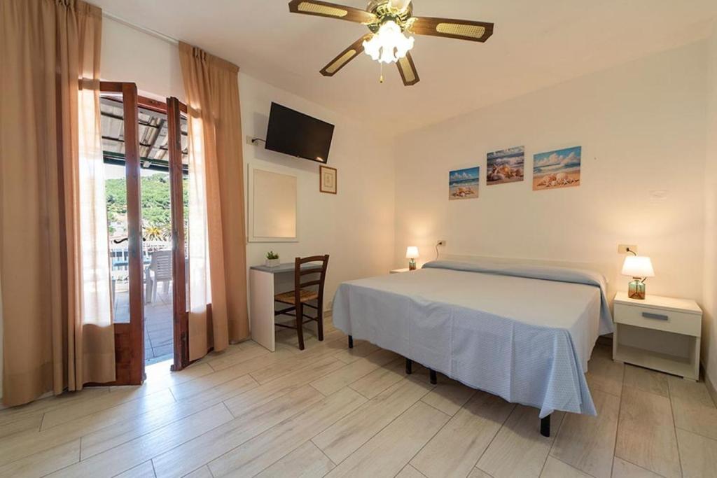 une chambre avec un lit et un ventilateur de plafond dans l'établissement Appartamenti Villa Miramare, à Capoliveri
