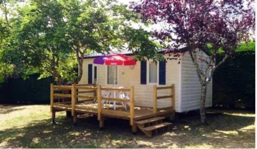 une petite maison avec une terrasse et un parasol dans l'établissement Camping 3 étoiles - Piscine - eehcdh, à Soturac