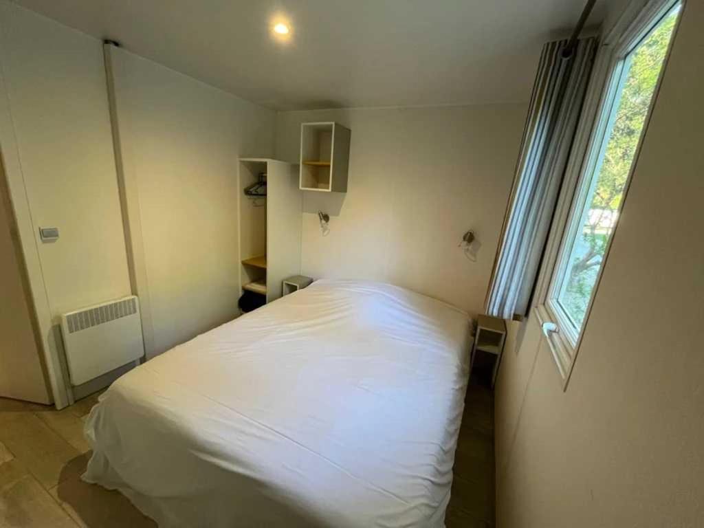 un lit blanc dans une chambre avec une fenêtre dans l'établissement Camping 4 étoiles - Piscine - ef00ai, à Avignon