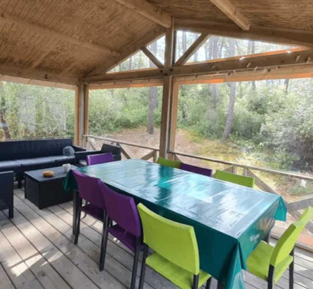 une véranda avec une table et des chaises dans l'établissement Camping 4 étoiles - Piscine - ccafgbh, à Saint-Hilaire-de-Riez