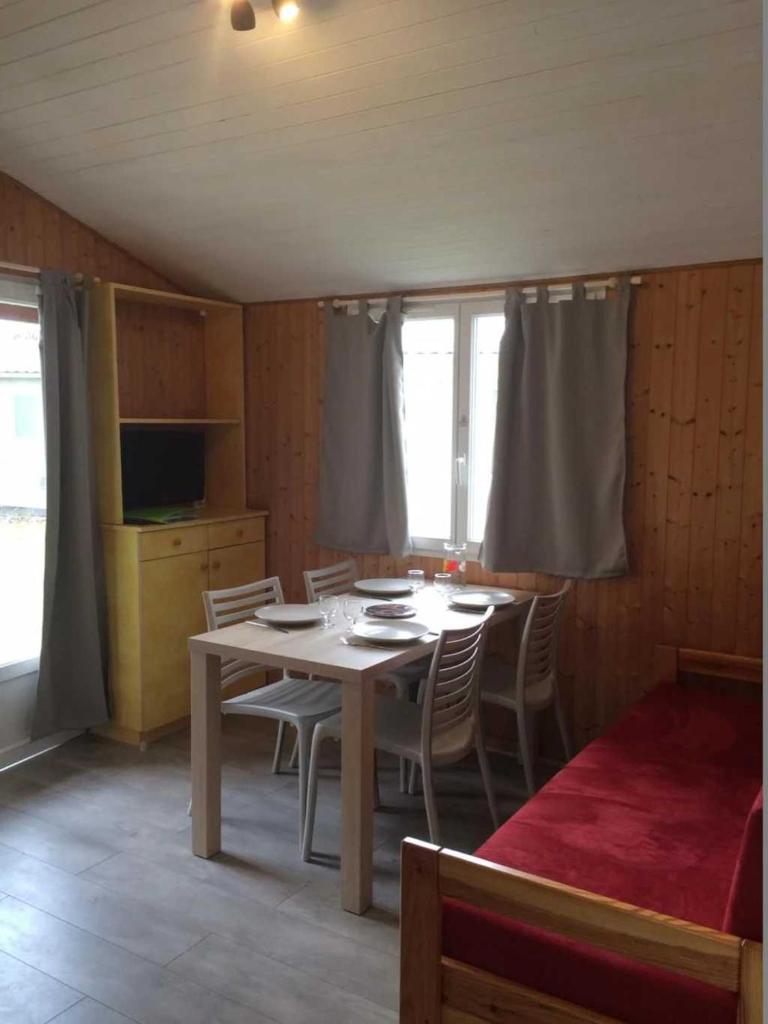 une salle à manger avec une table, des chaises et une télévision dans l'établissement Chalet 4 étoiles - Piscine - eehefh, à Coulon