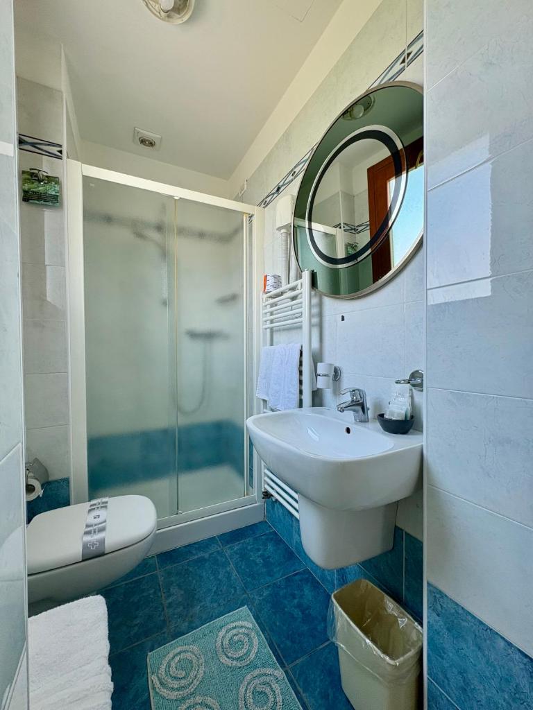 une salle de bain avec un lavabo, une douche et un miroir dans l'établissement Hotel Fortuna, à Chioggia