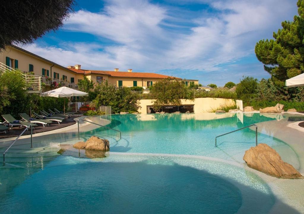 une piscine à l'eau bleue dans un complexe hôtelier dans l'établissement Tombolo Talasso Resort, à Marina di Castagneto Carducci