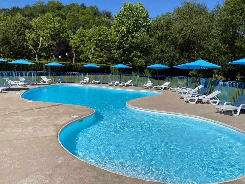 - une piscine avec des chaises et des parasols bleus dans l'établissement Complexe les 4 saisons, à Oust