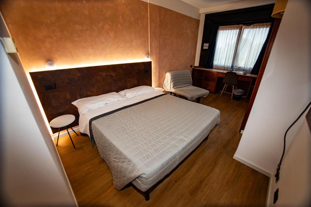 une chambre avec un grand lit blanc et une chaise dans l'établissement Hotel Sirena - B&B, à Cesenatico
