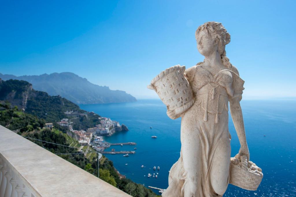 une statue d'un ange debout sur un rebord surplombant l'océan dans l'établissement Exclusive villa on the Amalfi coast, 300 steps from the road, à Amalfi