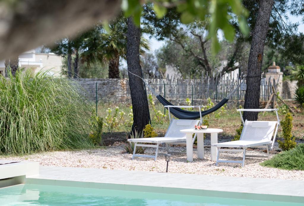 - deux chaises et un hamac à côté de la piscine dans l'établissement Villa Myricae by Bianco Puglia Vacanze, à San Vito dei Normanni