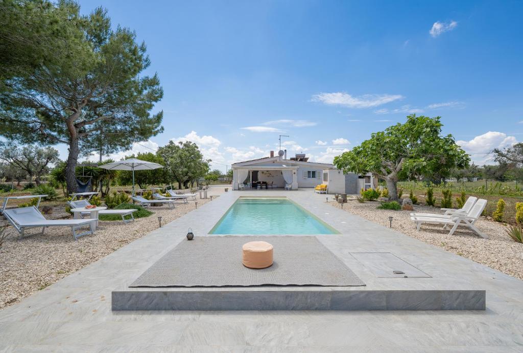 une piscine dans une cour avec des chaises et une maison dans l'établissement Villa Myricae by Bianco Puglia Vacanze, à San Vito dei Normanni