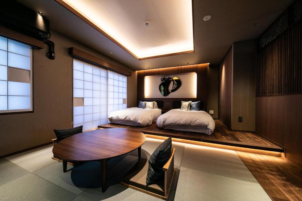 - une chambre avec 2 lits et une table en bois dans l'établissement Saigakukan, à Yufu