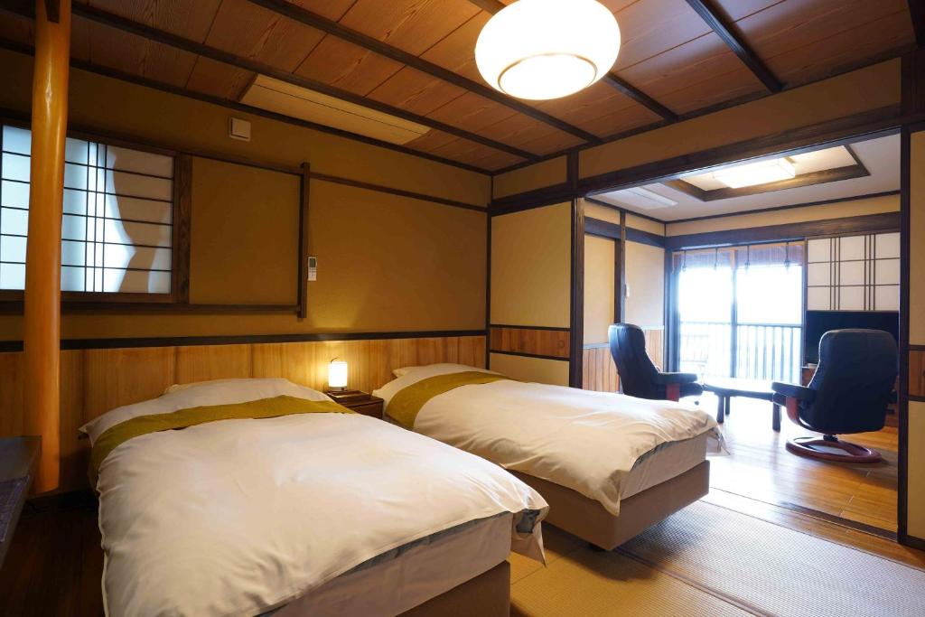 une chambre avec deux lits et un bureau et une fenêtre dans l'établissement 桐のかほり咲楽, à Kawazu