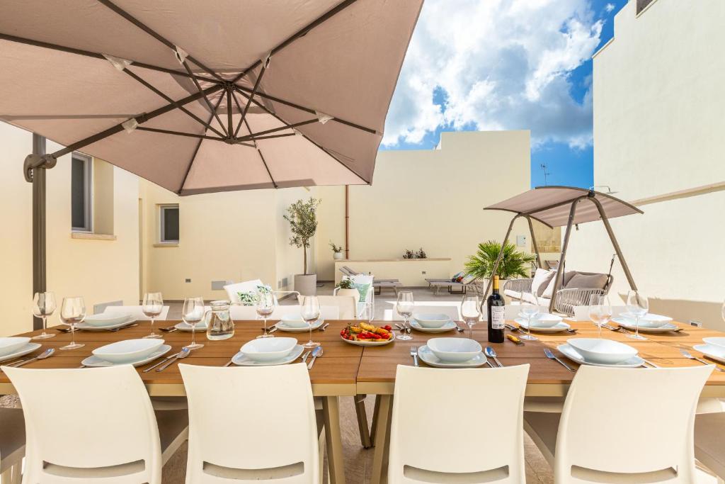 une table en bois avec des chaises blanches et un parasol dans l'établissement Villa Noemi Private Pool by HDSalento, à Leuca