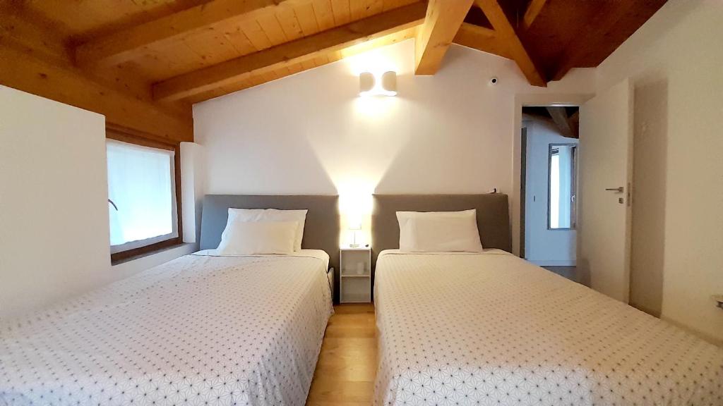 deux lits dans une chambre avec deux fenêtres dans l'établissement Holiday Home Villa Salici, pool & garden, à Colico