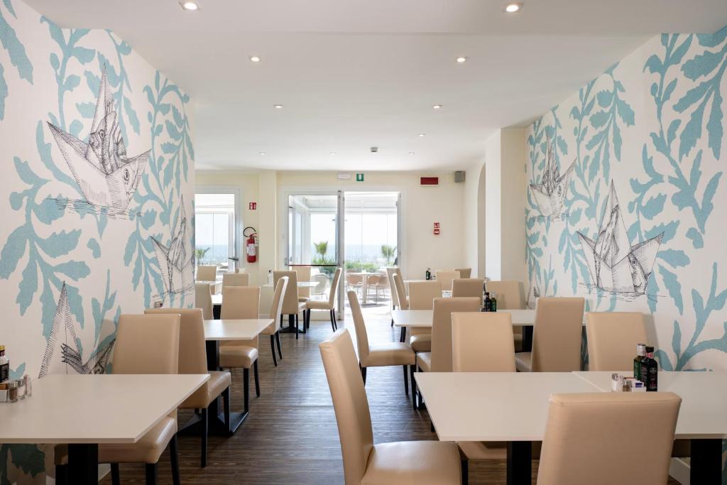 une salle à manger avec tables et chaises et papier peint fleuri dans l'établissement Hotel Astoria, à Caorle