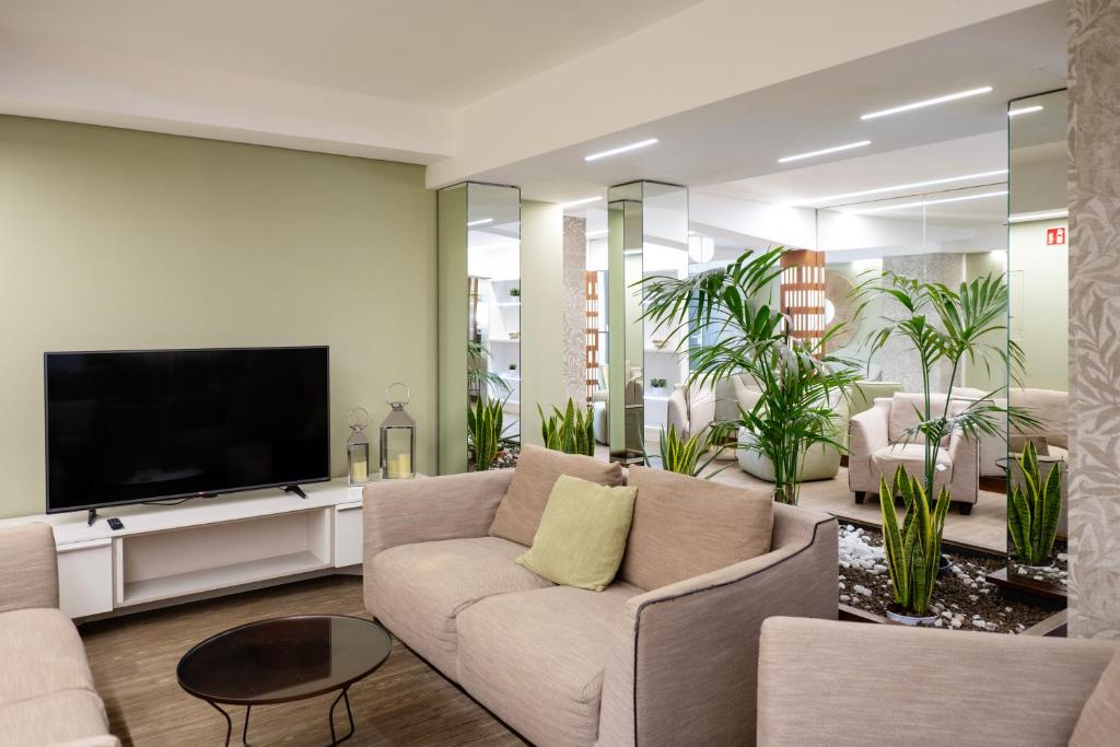 un salon avec un canapé et une télévision à écran plat dans l'établissement Hotel Astoria, à Caorle