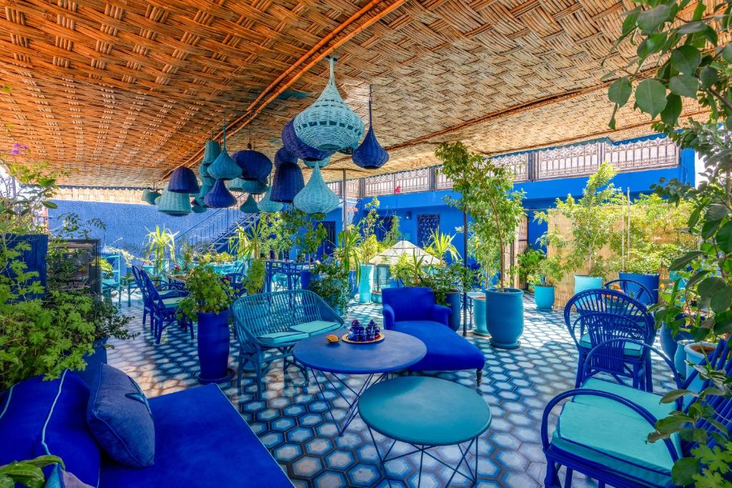 un patio avec des chaises bleues, des tables et des plantes dans l'établissement Riad Stella Cadente Marrakech, à Marrakech