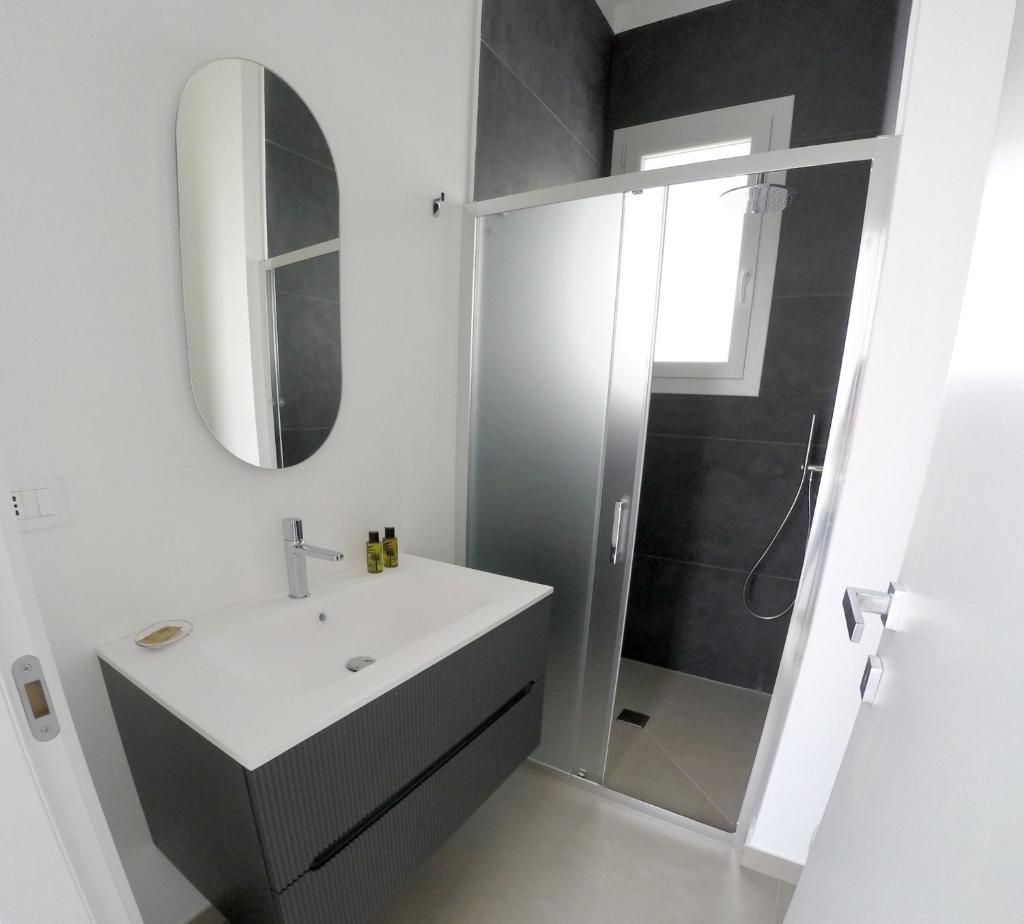 une salle de bain blanche avec un lavabo et une douche dans l'établissement Riflessi sul Plemmirio, à Plemmirio