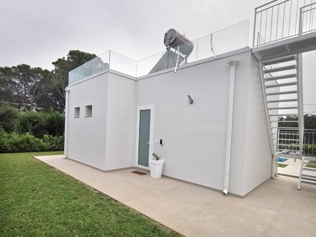 un bâtiment blanc avec une échelle et un balcon dans l'établissement Riflessi sul Plemmirio, à Plemmirio